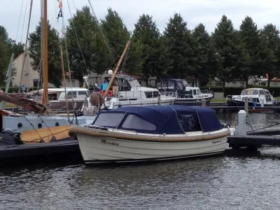 sloep met donker kap en vingersteiger in jachthaven