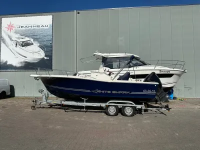 twee boten voor een loods op een parkeerterrein