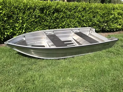 aluminium roeiboot op gras met haag