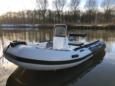 opblaasbare rib op rustig water, langs oever