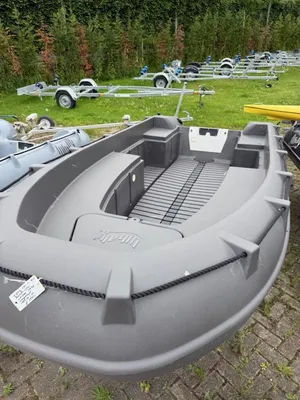 kunststof boot op gras met trailers op achtergrond