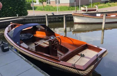 houten sloep afgemeerd bij kade