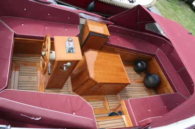 interieur van vlet met teakvloer en rode kussens