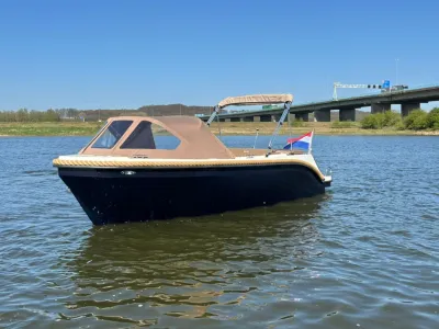 Tenderboot op water met brug op achtergrond