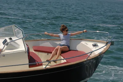 vrouw zittend op boeg van boot in zee