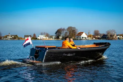 Zwarte sloep met twee personen op het water