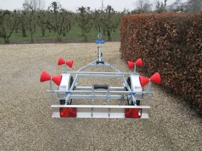 boottrailer op grindpad met haag en bomen