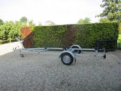 boottrailer op grind met haag op achtergrond