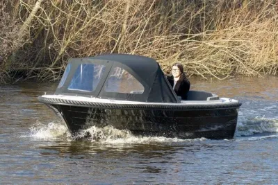 kleine zwarte motorboot met kap op het water