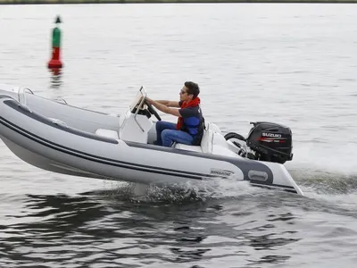 grijze rubberboot met bestuurder op water