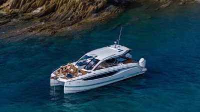 catamaran in helder water bij rotsachtige kust