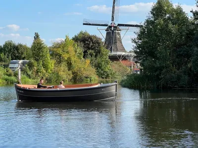 sloep op water met molen en bomen