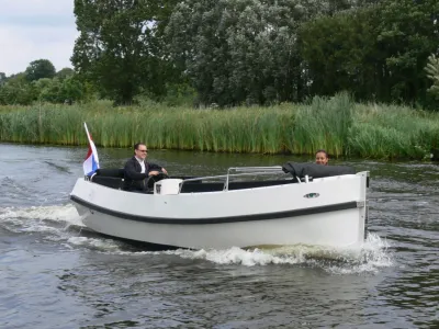 witte aluminium sloep varend op een kanaal