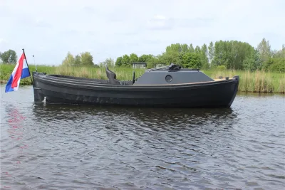 zwarte sloep op water bij rietkraag