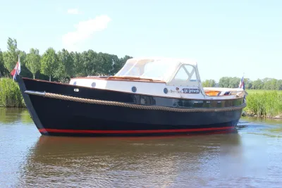 houten motorjacht in water bij oever
