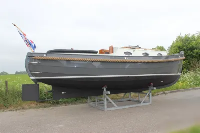 grijze sloep op trailer langs de weg