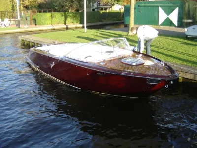houten sportboot afgemeerd bij kade