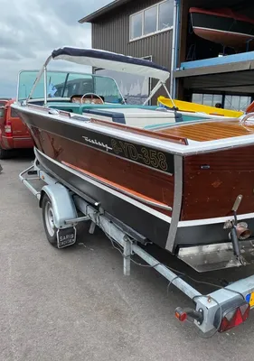 klassieke houten boot op trailer bij loods