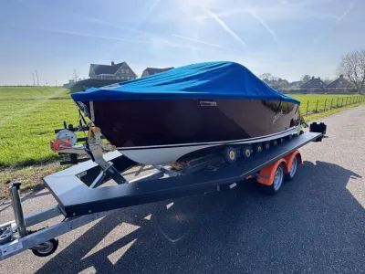 houten boot met blauwe hoes op trailer