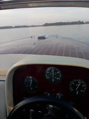 Zicht vanuit stuurstand op houten boeg en meer