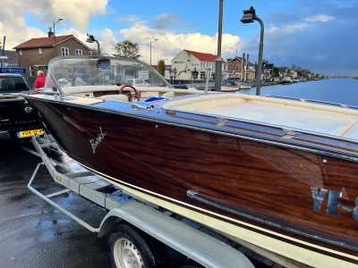 houten motorboot op trailer bij kade