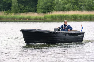 zwarte sloep met bestuurder op open water