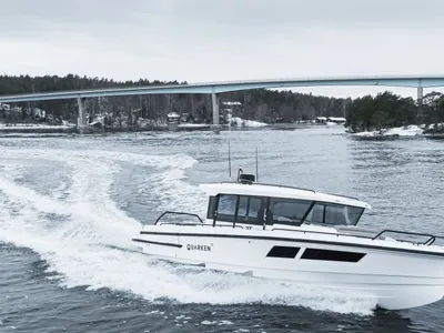witte kajuitboot op open water onder een brug
