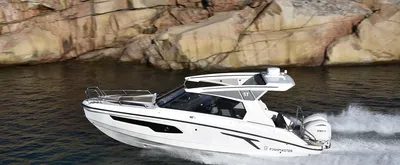 wit motorjacht varend langs rotsachtige kust