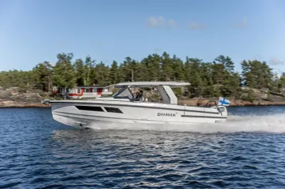 wit motorjacht varend langs rotsachtige kust