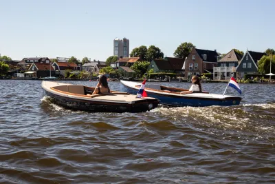 twee kleine sloepen op water met huizen op achtergrond