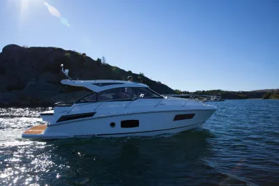 witte motorboot varend langs rotsachtige kust