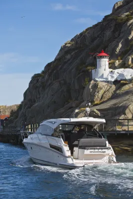 Motorboot bij rotsachtige kust met vuurtoren