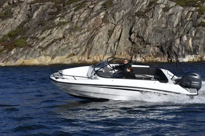 witte motorboot bij rotsachtige kust