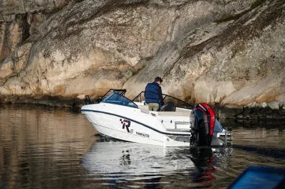 Boot bij rotskust met persoon aan boord