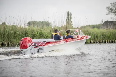 rood-witte motorboot met twee personen