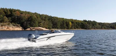 wit motorjacht varend langs beboste kust