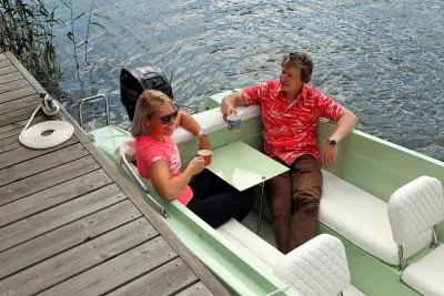 twee personen in kleine groene boot bij steiger