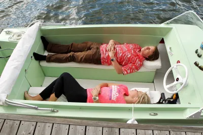 Twee mensen liggend in groen bootje aan steiger