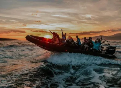 Ribboot met meerdere personen bij zonsondergang