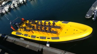 gele ribboot met meerdere zitplaatsen bij steiger