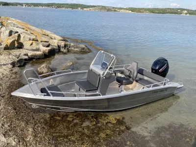 aluminium consoleboot in ondiep water bij rotsen