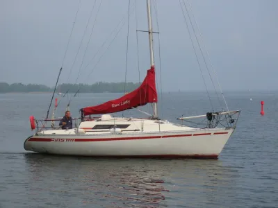 zeiljacht met rode zeilhoes op rustig water