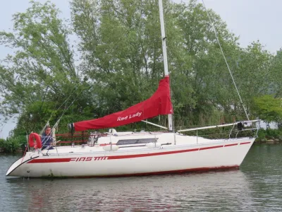 zeiljacht op rustig water met rode zeilhoes