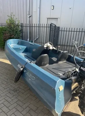 blauwe kleine motorboot op oprit bij hek en gebouw