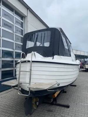 wit motorjacht op land bij loods