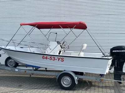 witte visboot met rode bimini op trailer