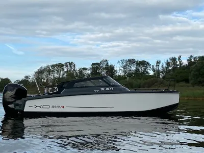 motorboot op het water voor een boomrijke oever