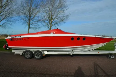rode sportboot op trailer naast gras
