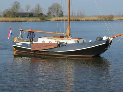 zeilboot op rustig water met persoon op dek