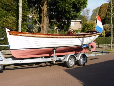 witte houten sloep op trailer met vlag